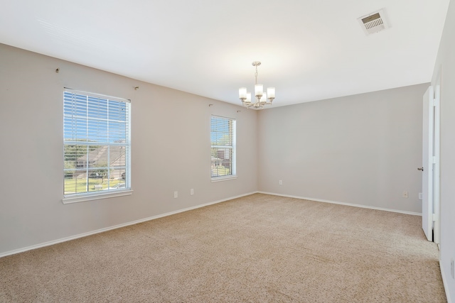 carpeted empty room featuring a notable chandelier