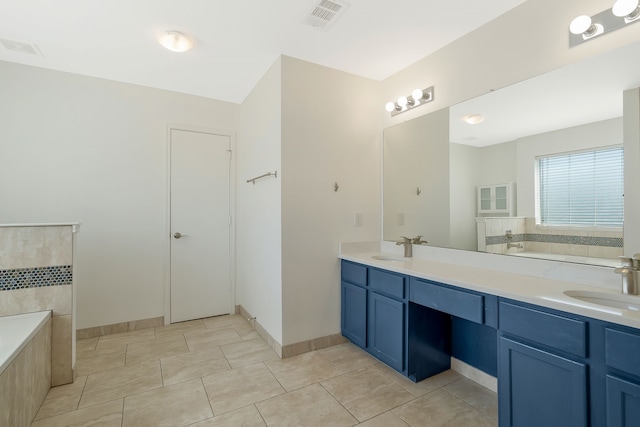 bathroom featuring tiled tub, vanity, and tile patterned flooring