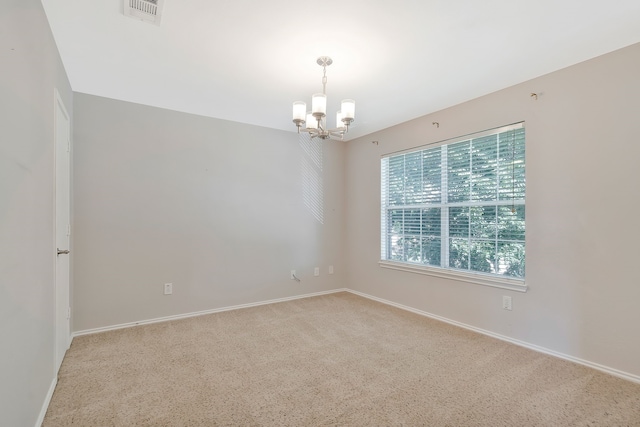 carpeted spare room with a notable chandelier