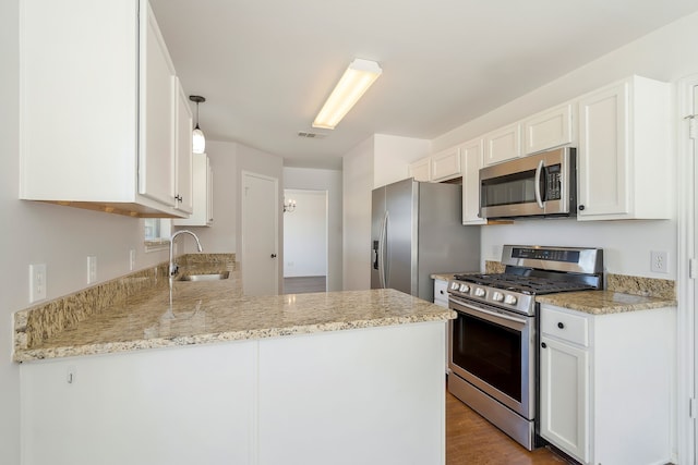 kitchen featuring decorative light fixtures, sink, kitchen peninsula, white cabinets, and appliances with stainless steel finishes