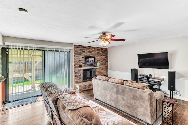 living room featuring a fireplace, ceiling fan, hardwood / wood-style floors, and a textured ceiling