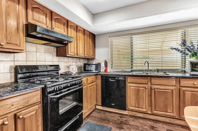 kitchen with black appliances, decorative backsplash, dark hardwood / wood-style floors, sink, and dark stone counters