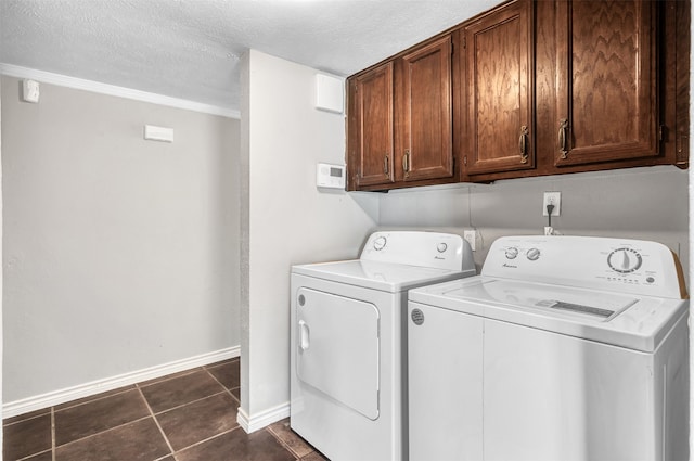 washroom featuring a textured ceiling, washing machine and clothes dryer, dark tile patterned floors, and cabinets