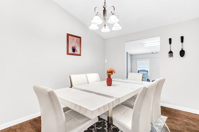 dining area with lofted ceiling, dark hardwood / wood-style floors, and an inviting chandelier