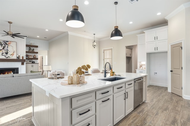 kitchen featuring ceiling fan, dishwasher, sink, hanging light fixtures, and an island with sink