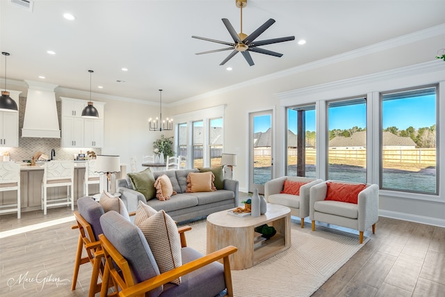 living room with ceiling fan with notable chandelier and crown molding