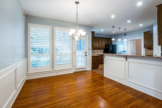 kitchen with light stone countertops, a center island, black appliances, tasteful backsplash, and sink