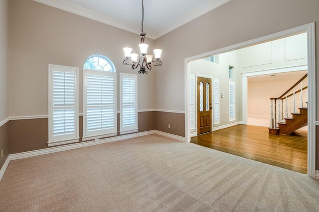 carpeted empty room featuring crown molding and a notable chandelier