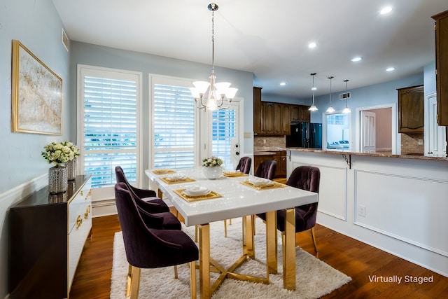 dining space with plenty of natural light, dark hardwood / wood-style flooring, and a notable chandelier