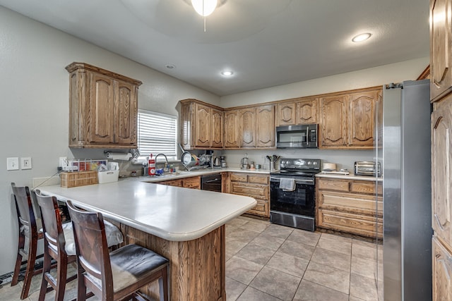 kitchen with sink, a kitchen breakfast bar, kitchen peninsula, light tile patterned floors, and appliances with stainless steel finishes