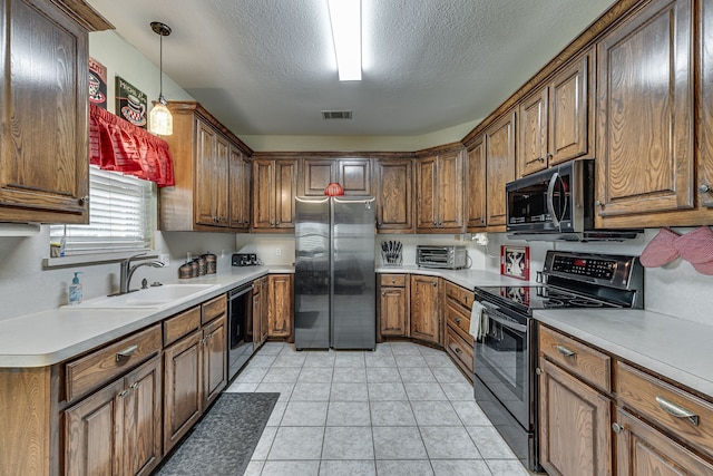 kitchen with sink, hanging light fixtures, a textured ceiling, light tile patterned flooring, and appliances with stainless steel finishes