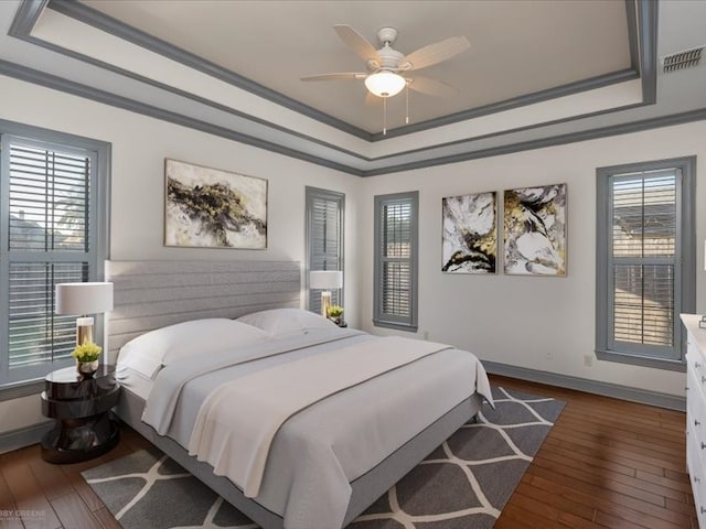 bedroom featuring a raised ceiling, ornamental molding, dark hardwood / wood-style flooring, and ceiling fan