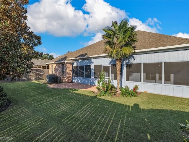 rear view of house featuring a sunroom, a yard, and a patio area