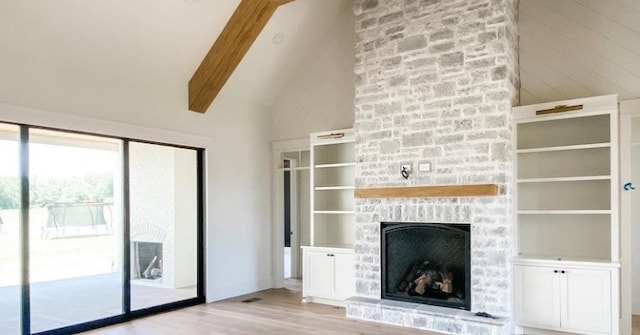 unfurnished living room featuring a fireplace, lofted ceiling with beams, and light hardwood / wood-style floors