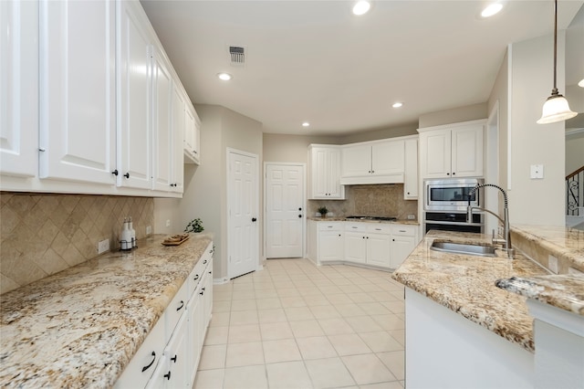 kitchen with light stone counters, sink, white cabinetry, appliances with stainless steel finishes, and decorative light fixtures