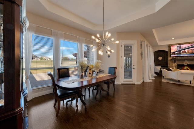 dining room featuring a raised ceiling, dark hardwood / wood-style floors, and an inviting chandelier