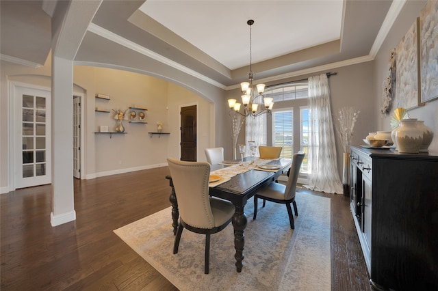 dining room featuring an inviting chandelier, a raised ceiling, crown molding, and dark hardwood / wood-style flooring