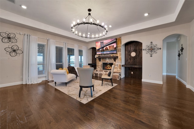 living room with a fireplace, a tray ceiling, and dark hardwood / wood-style flooring