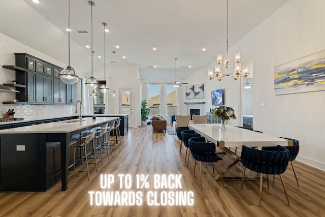 dining room featuring sink, high vaulted ceiling, ceiling fan, and light wood-type flooring