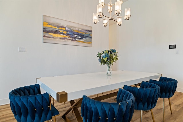 dining area featuring a chandelier, baseboards, and wood finished floors