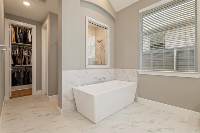 bathroom featuring walk in shower, a walk in closet, a soaking tub, and marble finish floor