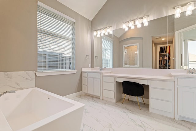 full bath with lofted ceiling, a soaking tub, double vanity, and marble finish floor