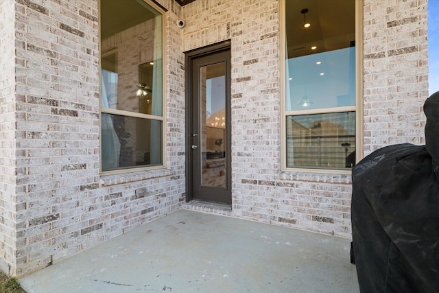 view of exterior entry with a patio and brick siding