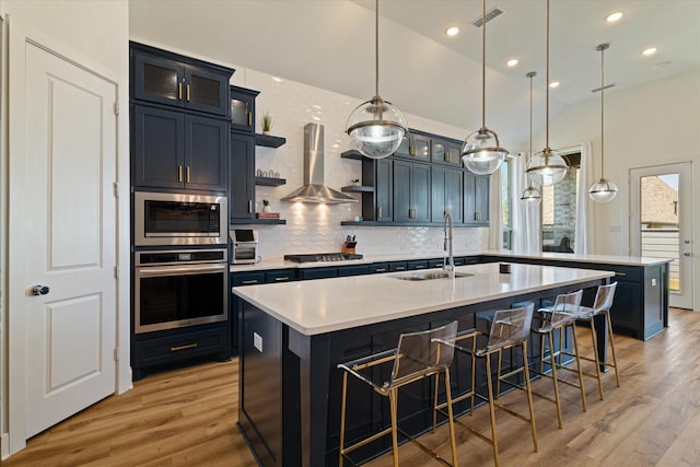 417 Sunnyridge Ln, Little Elm, TX 76227 - kitchen with appliances with stainless steel finishes, wall chimney range hood, a sink, open shelves, and light wood-type flooring