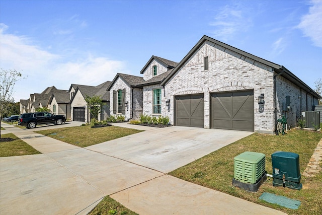417 Sunnyridge Ln, Little Elm, TX 76227 - french provincial home featuring an attached garage, concrete driveway, brick siding, and cooling unit