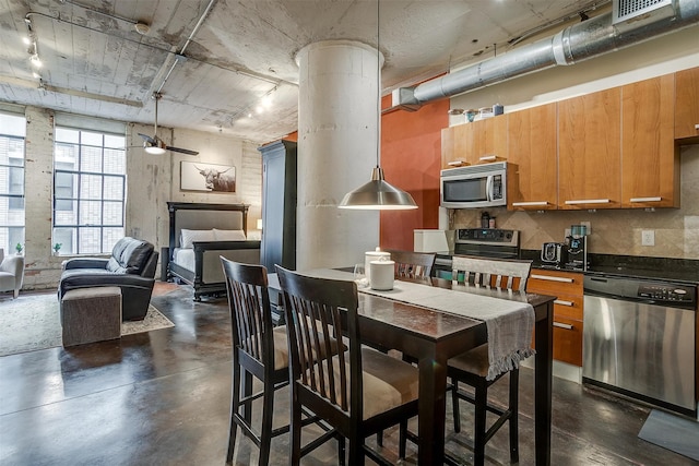 kitchen featuring ceiling fan, appliances with stainless steel finishes, hanging light fixtures, and ornate columns