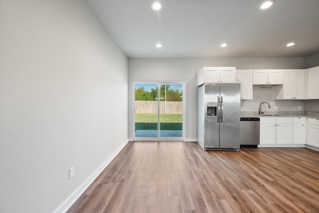 kitchen with sink, white cabinets, light wood-type flooring, and appliances with stainless steel finishes