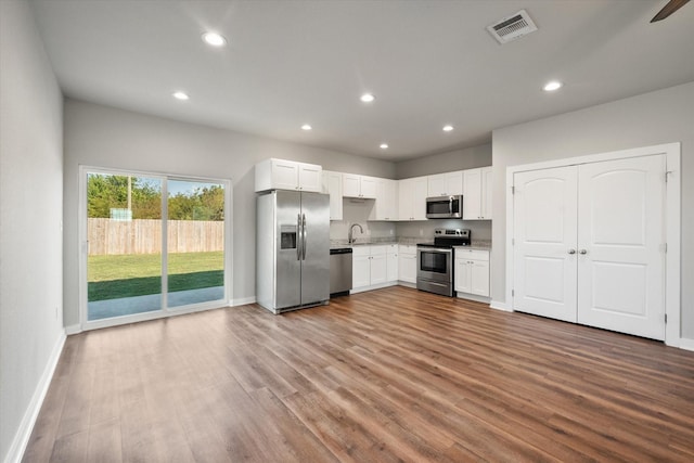 kitchen featuring stainless steel appliances, white cabinetry, light hardwood / wood-style floors, and sink