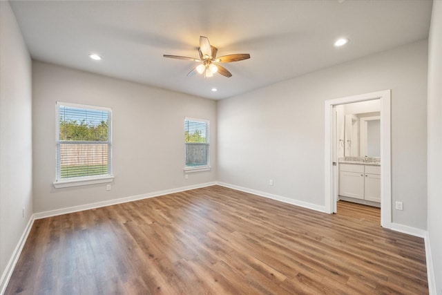 unfurnished bedroom featuring ensuite bath, ceiling fan, and light wood-type flooring