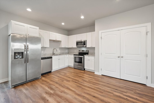 kitchen with white cabinetry, light hardwood / wood-style flooring, stainless steel appliances, and sink