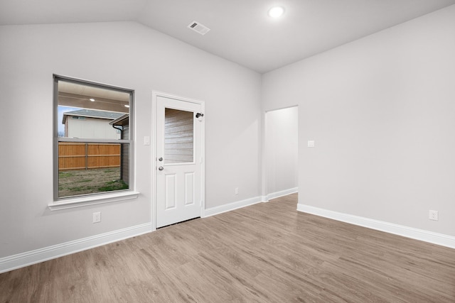 spare room featuring lofted ceiling, baseboards, visible vents, and wood finished floors