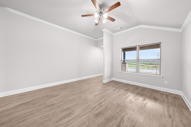 spare room with a ceiling fan, lofted ceiling, ornamental molding, visible vents, and wood finished floors