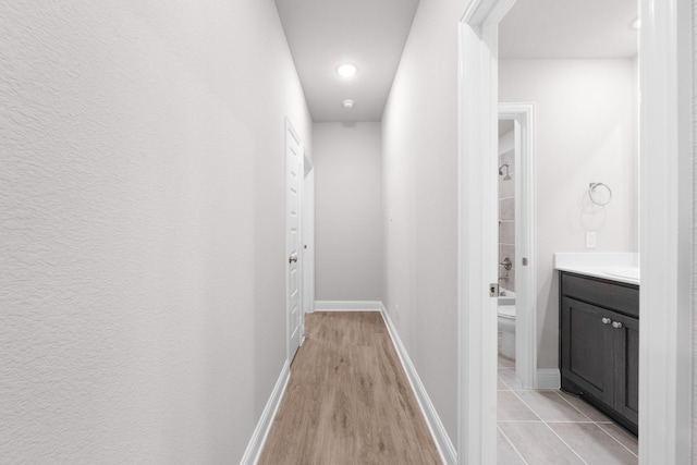 corridor featuring baseboards and light wood-style floors