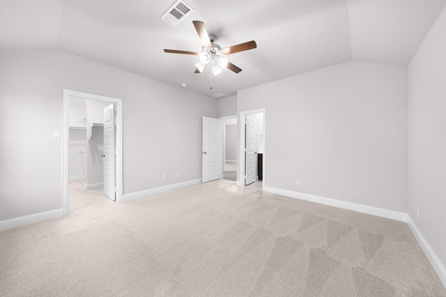 unfurnished bedroom featuring light carpet, a spacious closet, visible vents, and vaulted ceiling