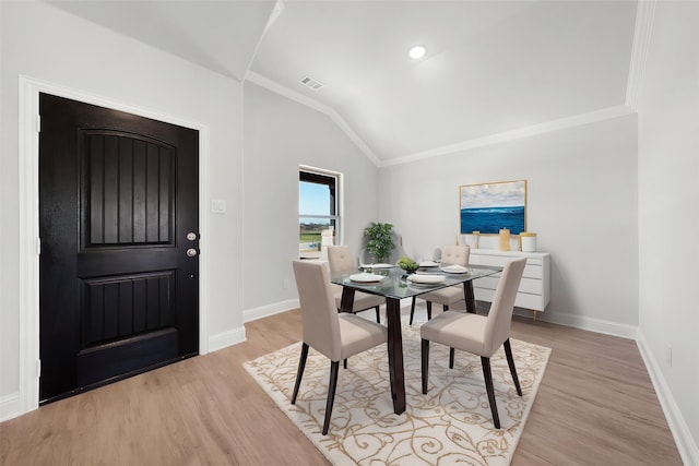 dining room with light wood finished floors, crown molding, visible vents, baseboards, and lofted ceiling