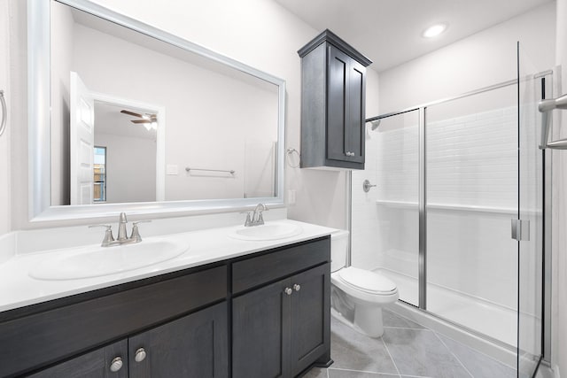 bathroom with double vanity, toilet, a stall shower, and a sink