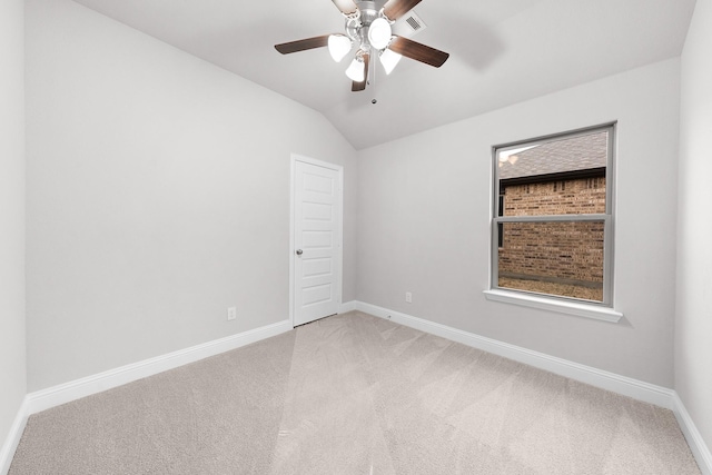 empty room with vaulted ceiling, light carpet, baseboards, and a ceiling fan