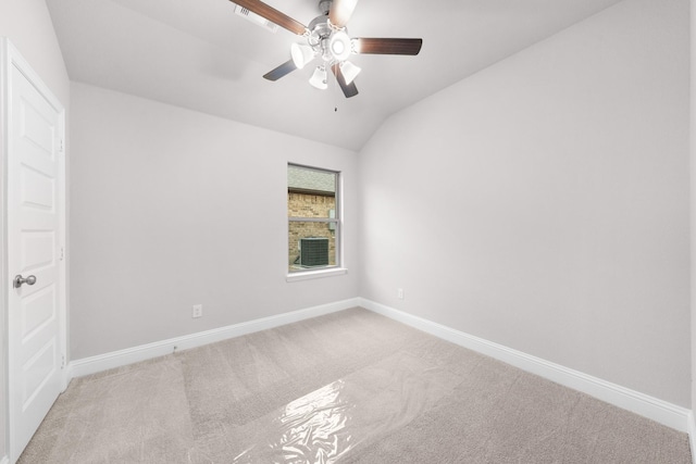 carpeted spare room with vaulted ceiling, baseboards, and a ceiling fan