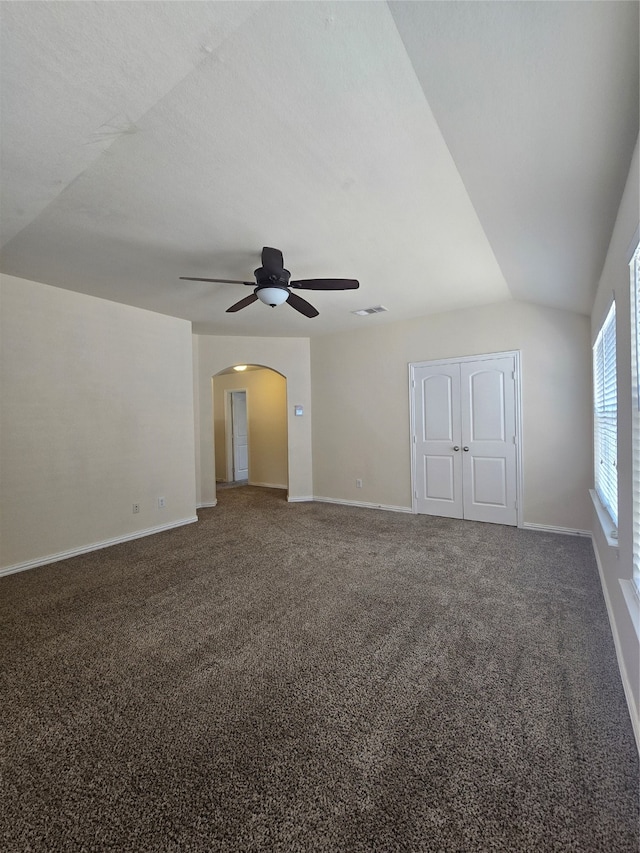 unfurnished bedroom featuring a closet, ceiling fan, vaulted ceiling, and dark colored carpet