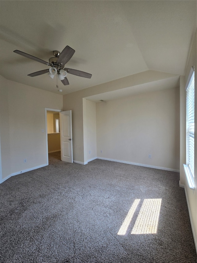 unfurnished room with dark carpet, vaulted ceiling, and ceiling fan