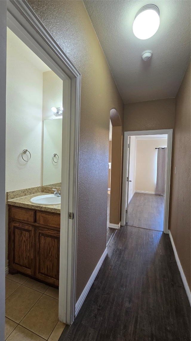 hallway featuring a textured ceiling, wood-type flooring, and sink