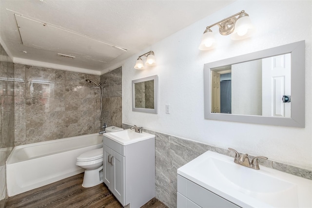 full bathroom featuring toilet, tile walls, tiled shower / bath combo, hardwood / wood-style flooring, and vanity