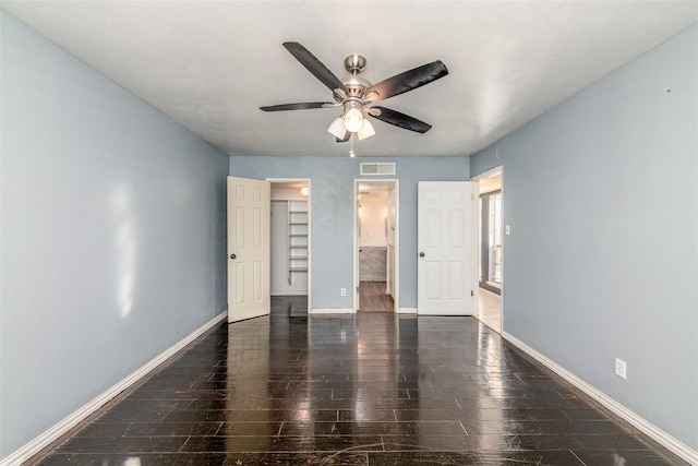 interior space with ceiling fan, connected bathroom, dark wood-type flooring, a closet, and a spacious closet