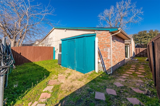 view of side of home with a storage unit and a lawn