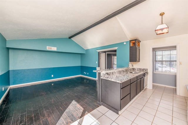 kitchen featuring lofted ceiling with beams, light stone countertops, dark brown cabinetry, sink, and dishwasher