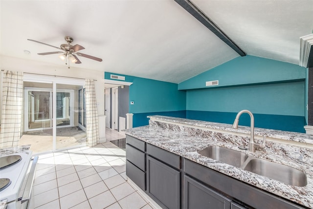 kitchen with light stone countertops, stainless steel range oven, sink, vaulted ceiling with beams, and light tile patterned floors